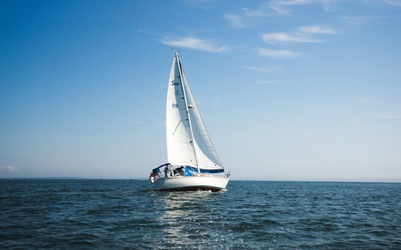 Sail boat sailing on the open waters under a blue sky.