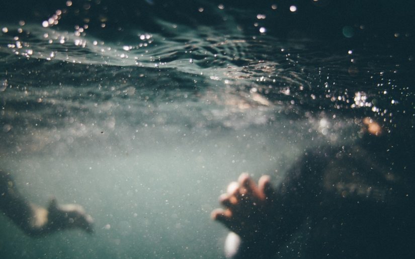 Underwater shot of two people who have fallen overboard from a boat.