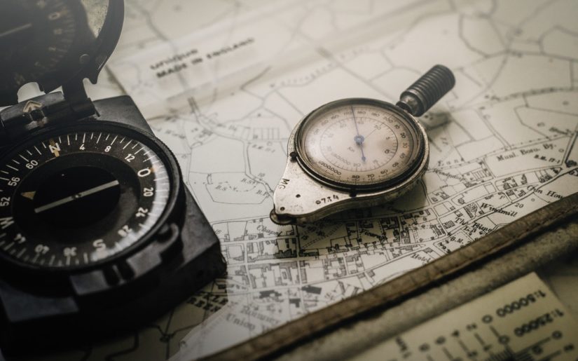 Close-up shot of a boating trip being planned using nuatical charts and compass.